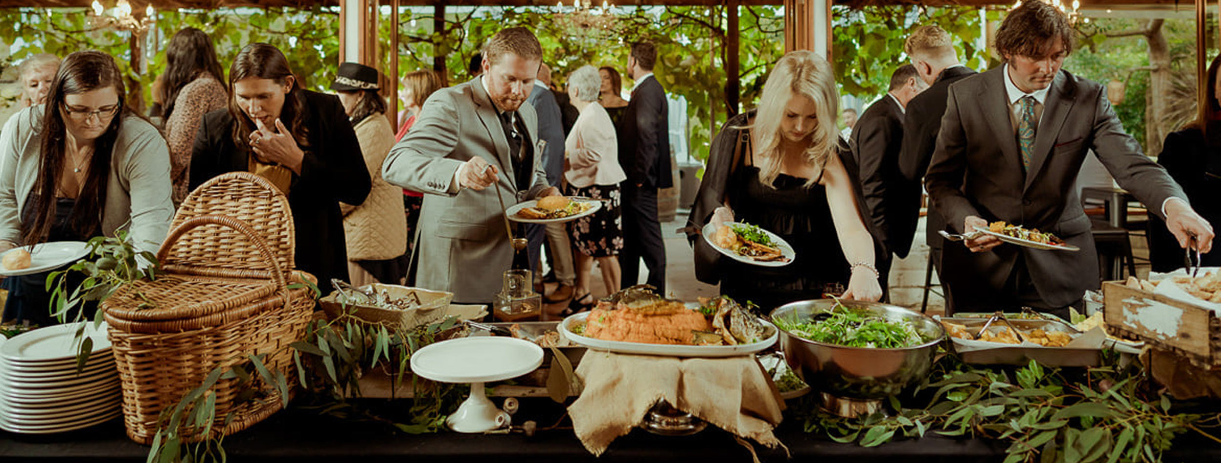 Guests at a wedding load up their plates with items from the buffte table